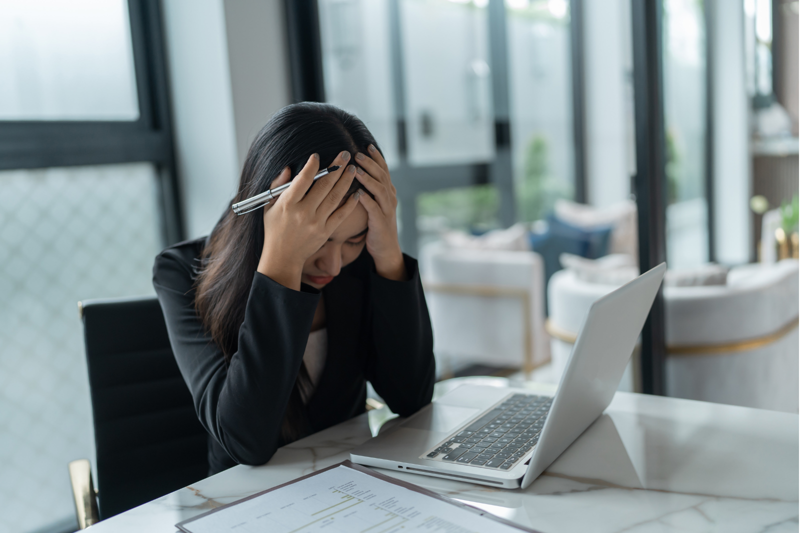 Overworked employee showing signs of burnout in a modern office while HR leaders monitor workload and team well-being.